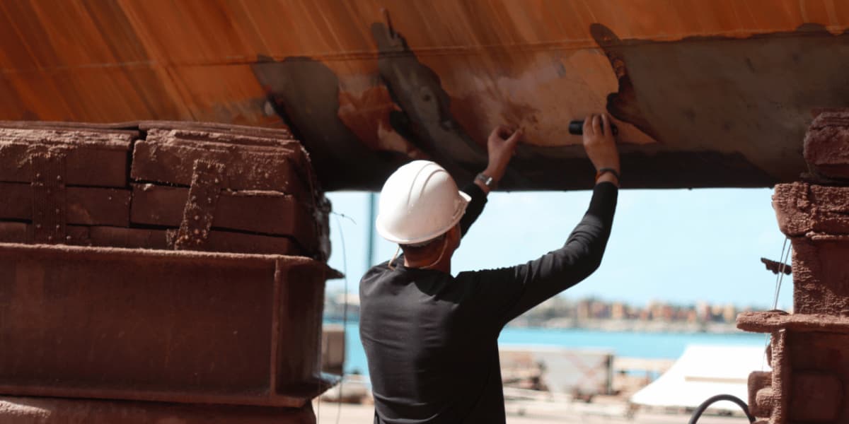Industrial technician inspecting the underside of a marine vessel