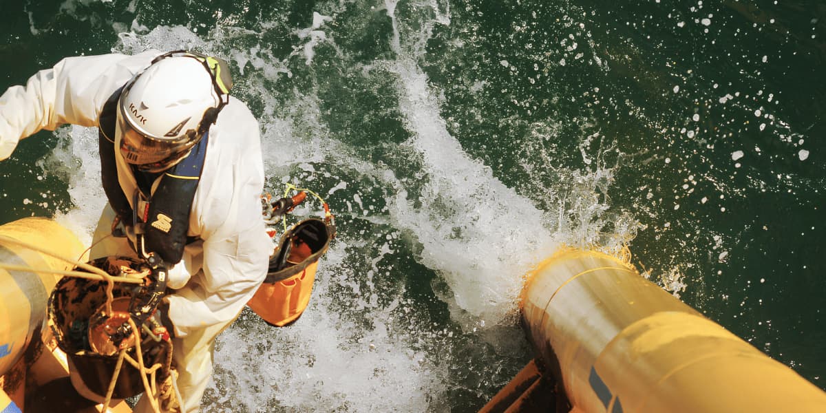 Rope access technician performing specialized work above the water on an offshore structure