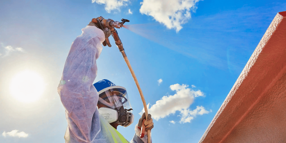 Technician spray applying protective coating to an industrial surface