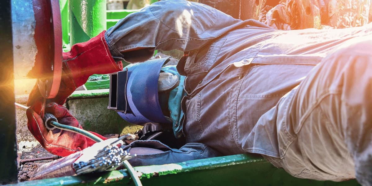 Trussco technician performing industrial welding and repair work in a confined area
